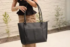 Cartera tote de cuero vacuno color negro, con forrería y cierre.