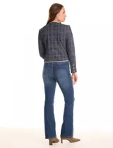 Chaqueta de tweed azul con sutiles destellos de lúrex, cuello a la base y abertura frontal. Tiene bolsillos delanteros decorativos y manga larga con tres botones metálicos dorados en cada puño. Las terminaciones del cuello, apertura frontal, bolsillos y ruedo tienen vivos a contratono. Forro interno a tono.