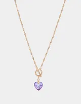Collar corto dorado con cadena de eslabones retorcidos y dije de corazón de cristal color lila.