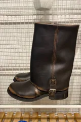 Bota de cuero color marrón oscuro con efecto desgastado, caña media, hebilla lateral y suela plana.