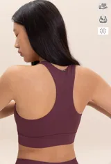 Top deportivo color borgoña con detalles de piping blanco en los bordes. El tejido Sense Pro® tiene tacto suave, transpirabilidad extrema y un soporte medio que realza las formas sin perder libertad.