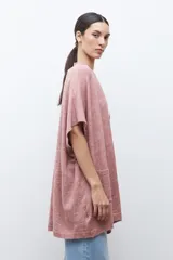 Ruana de tejido de punto color rosa melange, sin mangas y con cuello redondo.
