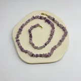 Collar de cuentas irregulares de lepidolita con cierre de mosquetón dorado de acero hipoalergénico.