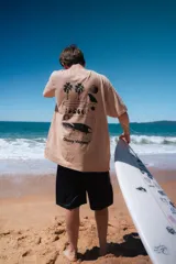 Remera beige de corte amplio con estampado en la espalda que incluye palmeras, fases lunares y una ola.