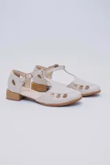 Sandalias bajas negras de cuero con pulsera al tobillo y talón cubierto. Presentan aberturas circulares en la capellada y taco de madera.