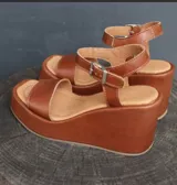 Sandalias de cuero color marrón con plataforma y taco ancho. Tiras anchas sobre el empeine y tobillo con hebilla metálica.