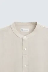 Camisa color beige claro de lino y algodón, corte relaxed fit, cuello mao, manga larga con puños abotonados y cierre frontal con botones. Marca Zara.