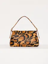 Cartera tipo baguette con estampado animal print de leopardo, confeccionada en cuero con pelo y detalles en cuero vacuno flor. Tiene correa regulable en combinación de cuero y pelo, con hebillas metálicas personalizadas.
