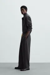 Sobrecamisa negra de corte amplio, con cuello solapa, manga larga con puños abotonados, bolsillos de parche en el pecho, bolsillos laterales y cierre frontal con botones.