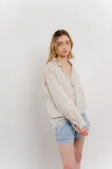 Camisa color crema de manga larga con cuello camisero y detalles de encaje en el escote. Se ata en la parte delantera.