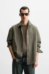Camisa de hombre regular fit, color blanco con rayas verticales negras, cuello solapa, manga larga con puños abotonados y cierre frontal con botones.