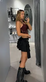Minifalda negra de tiro bajo con volados y detalle de hebilla metálica en la cintura.