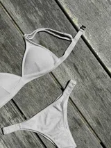 Conjunto de bikini turquesa con corpiño triangular de corte fijo, breteles regulables y almohadillas desmontables, y bombacha vedetina con frunce elástico en los costados.