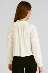 Blusa blanca de viscosa con cuello en V, volados, cordón y borlas.