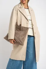 Tapado largo color beige claro, de corte oversize, con cuello solapa y cierre frontal de botones.