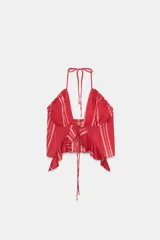 Top corto con escote pico y tirantes finos, color rojo con rayas verticales blancas. Detalle de volantes en el mismo tejido y lazada en el delantero.