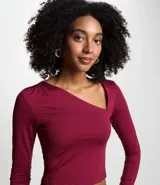 Blusa corta color borgoña, de mangas largas y escote asimétrico.