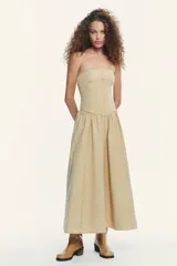 Vestido midi color beige, de corte recto, con escote palabra de honor y hombros descubiertos. Confeccionado en tejido con efecto lavado y detalle de pliegues. Cierre trasero con cremallera metálica.
