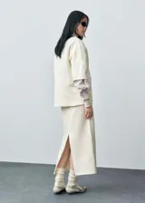 Jersey color crema de punto fino, con cuello redondo, manga corta y diseño oversize.
