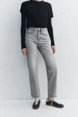 Pantalón de jean gris de tiro alto, corte mom fit, con trabillas y cinco bolsillos. Cierre frontal con cremallera y botón metálico.