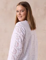 Blusa blanca de broderie con cuello a la base y escote en V. Apliques de brillos y piedras nacar en la parte delantera.