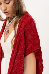 Ruana tejida de hilo color rojo con lurex y terminación de flecos.
