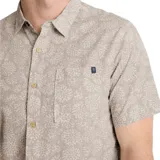 Camisa de manga corta color gris con estampado de hojas en blanco. Tiene cuello clásico, cierre con botones y bolsillo en el pecho.