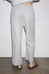 Pantalón culotte color crudo, de tiro medio, cintura elástica ajustable con cordones y bolsillos laterales ocultos en la costura.