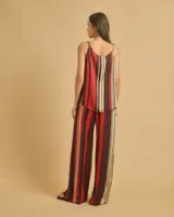 Top fluido con tirantes finos trenzados y escote barco, con estampado de rayas verticales rojas, azules y amarillas.