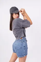 Remera gris oscuro con efecto lavado, corte crop y estampado frontal de mariposa con detalles tribales en negro.