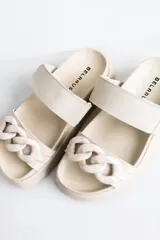 Sandalias de cuero color beige con plataforma y detalle de cadena de eslabones grandes en la tira delantera.