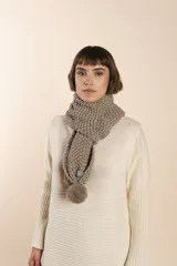 Bufanda tejida a mano en punto arroz color beige, con pompones en los extremos.