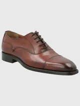 Zapato formal de cuero color marrón con punta alargada y cordones.