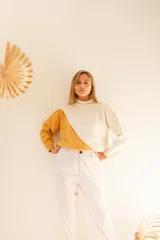 Sweater de punto color crema y mostaza, con cuello cisne y diseño asimétrico.