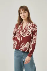 Camisa de poliéster con estampado floral en tonos borgoña y crema, corte holgado, cuello mao y cierre frontal con botones.