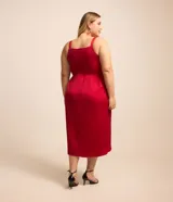 Vestido midi plus size de tela satinada color rojo, con breteles anchos, escote drapeado, cierre por cremallera en la espalda y pollera cruzada.