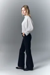 Pantalón de jean negro de pana, de tiro medio, ajustado en la cintura y con pierna levemente acampanada.