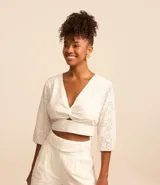 Blusa cropped de laise blanca con escote en pico, detalle torcido en el busto y manga corta abullonada.