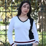 Suéter bicolor blanco y negro con cuello en V y volado vertical en el delantero. Puños y ruedo acanalados con vivo rayado negro y rojo.