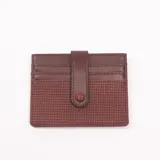 Tarjetero de cuero color bordó con textura tejida y cierre con broche a presión.