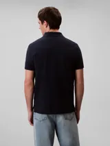 Chomba de piqué de algodón color azul marino, corte clásico, cuello polo con dos botones y logo CK bordado en rojo en el pecho.