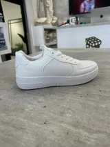 Zapatillas urbanas blancas de cuero sintético con cordones y suela de goma.