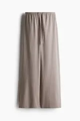 Pantalón largo color topo de punto de algodón, con cintura elástica ajustable con cordón fino. Tiene bolsillos laterales discretos y corte recto.