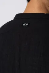 Camisa de lino blanca de manga larga, con cuello clásico y cierre frontal con botones. Corte recto y holgado.