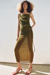 Falda larga color verde oliva, de tiro medio y corte recto. Presenta una superposición de tela tipo pareo ajustable con lazadas.