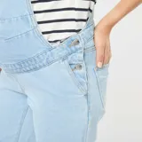 Enterito de jean celeste claro, estilo peto o jardinero, con panel elástico para maternidad sobre el abdomen. El corte de las piernas es recto y holgado.