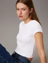 Remera blanca de algodón, corte slim y largo cropped, con cuello redondo y mangas cortas.