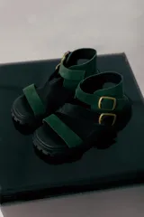 Sandalias de cuero marrón con tiras cruzadas y hebillas doradas.