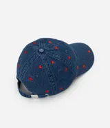 Gorra de béisbol de denim azul, con visera curva y bordados pequeños de corazones rojos.