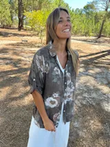 Camisa de algodón color chocolate con estampado floral en tonos beige. Cuenta con cuello camisero, cierre frontal de botones y mangas largas con trabas para arremangar.